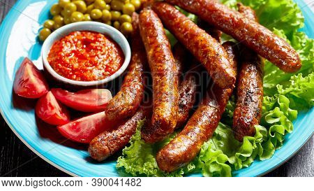 English Meal: Pork Sausages Chipolata Roasted And Served On A Blue Plate With Tomato Ketchup, Tomato