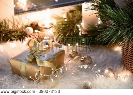 Christmas Golden Gift On Warm Windowsill With Garland, Fur, Candles, Baubles And Basket. Cozy Home. 