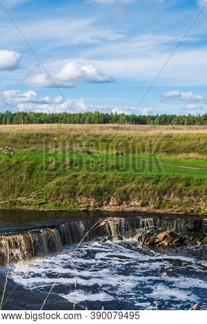 Waterfall, Water Flowing From The River Falls Down. A Stormy River With A Brown Hue.
