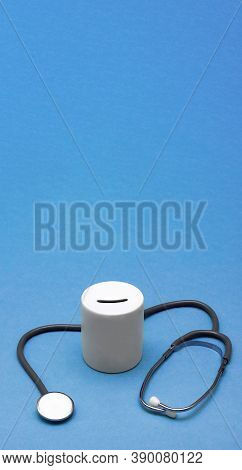 Cost Of Healthcare. Money Box With A Medical Doctors Stethoscope On Blue Background. Place For Text.