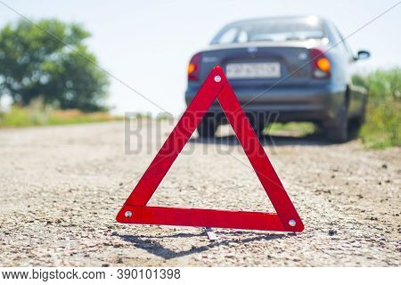 Red Warning Triangle With A Broken Down Car. A Car With A Breakdown Alongside The Road.