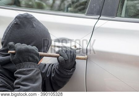 Male Thief Going To Break Car Window With Crowbar. Car Theft - Thief Trying To Break Into The Vehicl