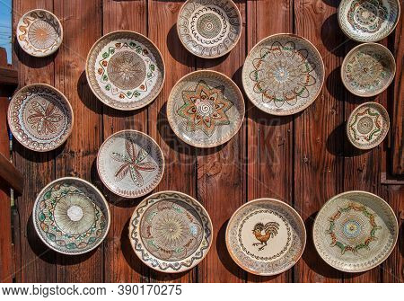 Romanian Traditional Ceramic Plates From Horezu Area, Romania, Placed Ornamentally On A Rustic Woode
