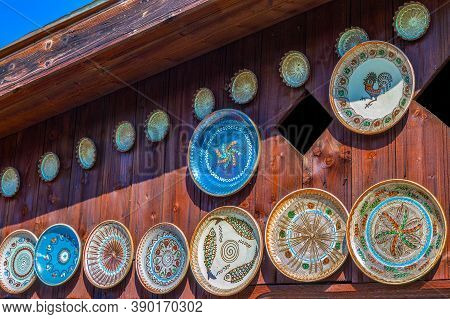 Romanian Traditional Ceramic Plates From Horezu Area, Romania, Placed Ornamentally On A Rustic Woode