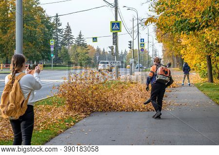 Moscow Russia. October 11, 2020 A Utility Worker Uses A Blower To Remove Fallen Leaves In An Alley I