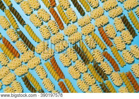 Raw Colored Fusilli And Radiatori Type Of Pasta On Blue  Background.
