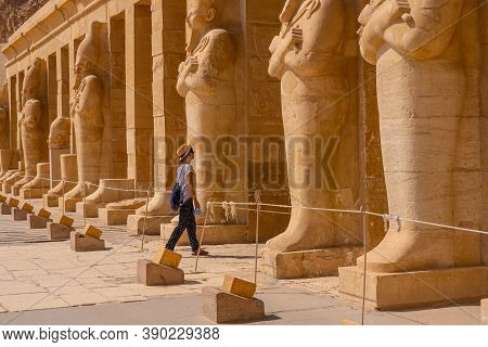 A Young Woman With Pharaoh Sculptures Entering Hatshepsut's Funerary Temple In Luxor. Egypt