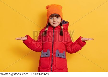 Female Child Spreading Palms Aside And Looking Directly At Camera, Posing Isolated Over Yellow Backg