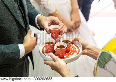 Closeup Of Bridegroom Holding Tea To Serve Elderly During Chinese Wedding Tea Ceremony. Chinese Word