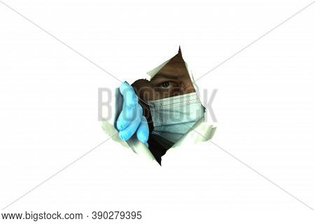 A Man In A Mask And Gloves Looks Through The Hole. Situation A Man In A Medical Mask Peeps Through A