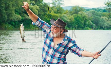 Fishing. Handsome Fisherman Fishing In A River With A Fishing Rod. Man Fisherman Catches A Fish