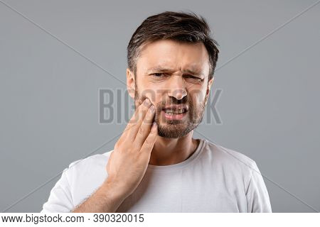 Teeth Problem. Man Suffering From Strong Tooth Pain, Grey Studio Background, Copy Space. Upset Middl