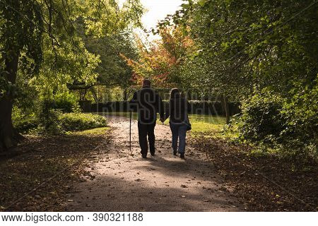 Hexthorpe, Doncaster, England - October 7, 2020. Man Leaning On A Wooden Crutch Walking Hand In Hand