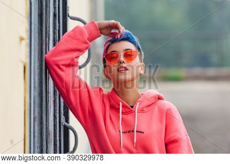 Portrait Of A Young Girl With Short Colorful Hair And Nose Piercing Satanding Near The Wall With Woo