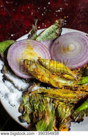 Closeup Of Cooked Indian Carplet Fish Or Mourala Fish With Onion Slices And Spices In Vertical Orien