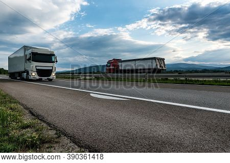 White Semi Trailer Lorry Truck Passing Another Truck On A Highway Driving At Beautiful Dramatic Suns
