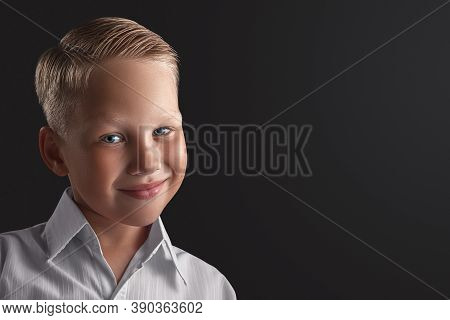Blond Boy With Blue Eyes Smiles On A Black Background. Close Ap. Copy Space