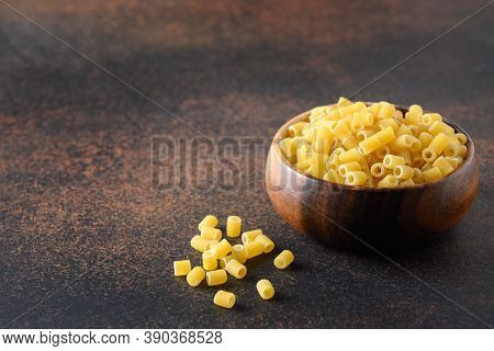 Ditalini Soup Pasta In Wooden Bowl Isolated On Brown Table. Close Up.
