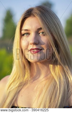 Overlight Bright Portrait Of A Charming Attractive Blonde In Flowery Dress In The Field