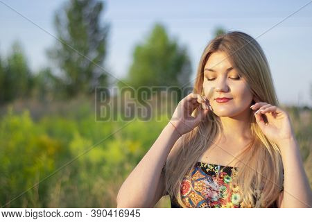 Overlight Bright Portrait Of A Charming Attractive Blonde In Flowery Dress In The Field
