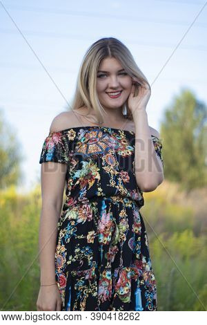Overlight Bright Portrait Of A Charming Attractive Blonde In Flowery Dress In The Field