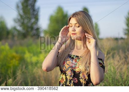 Overlight Bright Portrait Of A Charming Attractive Blonde In Flowery Dress In The Field