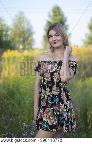 Overlight Bright Portrait Of A Charming Attractive Blonde In Flowery Dress In The Field