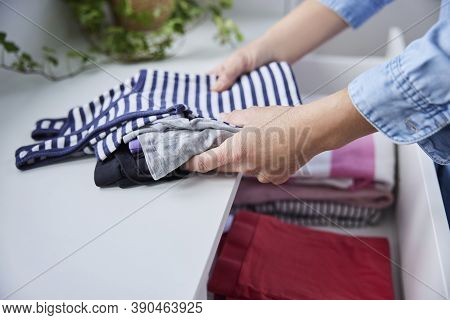 Close Up Of Woman Folding Up Clothes And Tidying Them Into Drawers