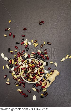 Mix Of Various Dry Legumes In Ceramic Bowl, Scattered On Black Stone Background