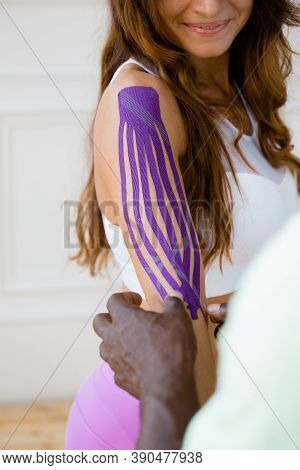 African American Man Glues A Kinesitherapy Plaster To A Womans Shoulder Joint