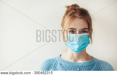 Red Haired Caucasian Woman With Freckles Is Wearing A Medical Mask And Looking At Camera On A White 