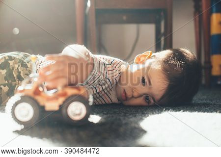 Caucasian Boy Lying On The Floor And Playing With A Toy Car During A Sunny Day