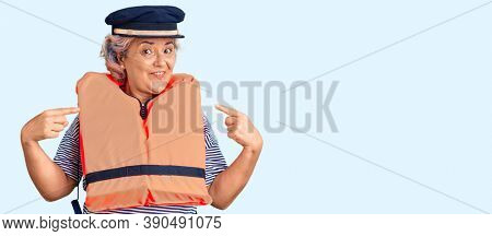 Senior woman with gray hair wearing nautical lifejacket pointing finger to one self smiling happy and proud 