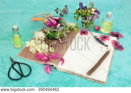 Naturopathic herbal medicine with summer flowers & herbs loose & steeping in a jar with oils for aromatherapy essential oil. Still life with old hemp notebook & rustic pencil. Natural health care.