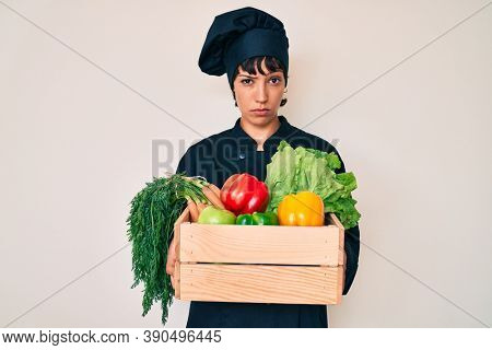 Beautiful brunettte woman chef holding fresh veggetables skeptic and nervous, frowning upset because of problem. negative person. 
