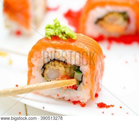 Man Holding Wooden Chopsticks Sushin, On Top Of Wasabi Sushi. White Background.