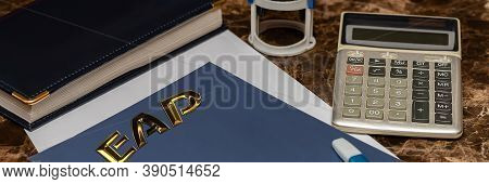 Eap Employee Assistance Program. Gold Letters On A Blue Piece Of Paper, Near A Calculator And A Diar