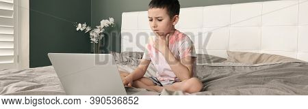 Boy Child Sitting In Bed And Learning Online On Laptop Internet. Self Isolation At Home. Distant Rem
