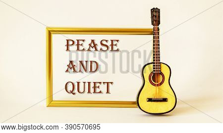 Pease And Quiet , The Text Is Written In A Gold Frame On A White Background. Guitar Is Nearby.