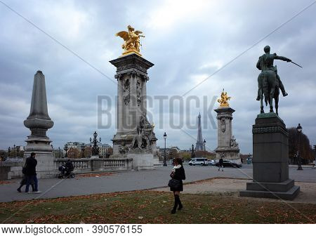 Paris, France - November 19, 2018: Everyday life photo in city centre. Socle counterweights of Pont Alexandre III with Gilded Fames sculptures. Grey cloudy weather