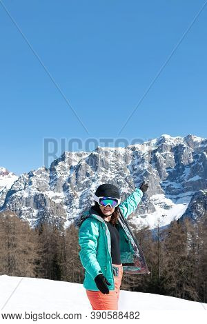 A Woman In A Colorful Ski Suit, Helmet And Sunglasses After Skiing Stands Against The Backdrop Of Mo