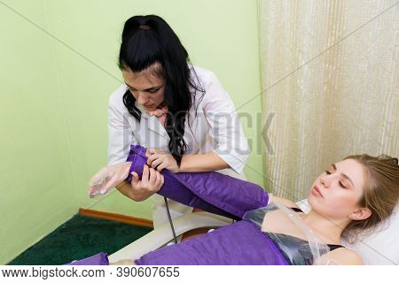 Young Beautiful Woman Is Being Prepared For Pressotherapy Procedures While Lying On A Couch.