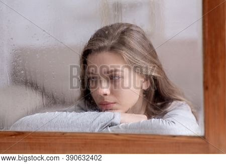 Unhappy Young Lady Looking Out Window With Drops Of Rain, Feeling Sad Or Melancholic. Emotional Woma