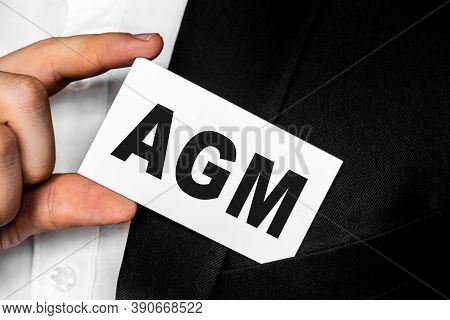 A Man In A Black Business Suit Lowers Or Removes From His Breast Pocket A White Business Card With T