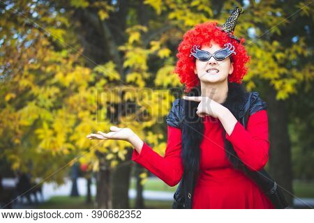 Creative Image Of A Young Woman In A Red Dress. Halloween Carnival Party. Beautiful Rabid Clown In A
