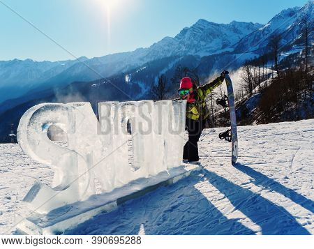 Russia, Sochi 21.01.2020. Girl With A Snowboard Bent Over With Her Mouth Open To The Ice Inscription