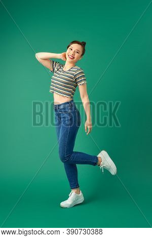 Joyful Young Asian Woman Standing On One Leg. Full Length View Of Blissful Girl Dancing On Green Bac