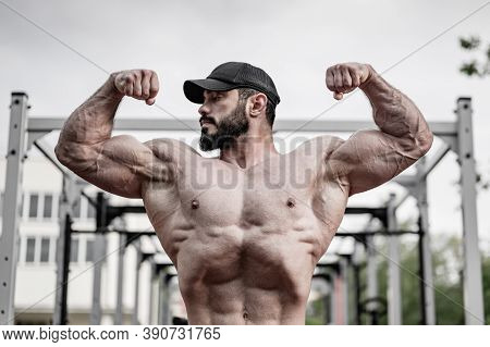 Handsome Young Bearded Male Showing Double Biceps Muscle On Street Gym Outdoor Workout Sport Ground 