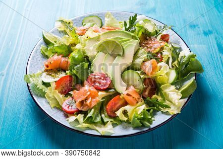Healthy salad with smoked samlmon and avocado on cyan vackground