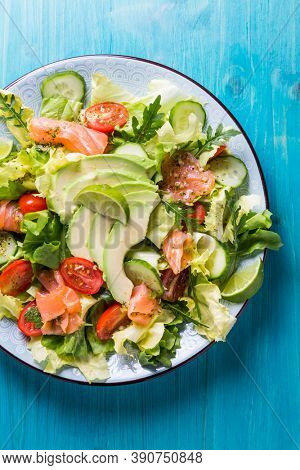 Healthy salad with smoked samlmon and avocado on cyan vackground